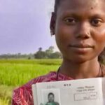 A woman stands in a field showing up a legal document