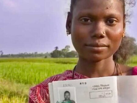 A woman stands in a field showing up a legal document