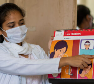 A women in a mask shows medical information on a flip chart