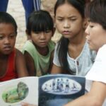 A woman reads a picture book aloud while children listen intently