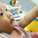 A healthy baby is surrounded by toys