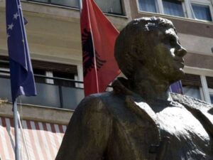 A statue of a man is in front of two flags