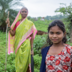 A woman and a girl stand in a field.